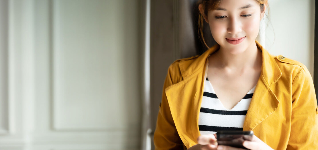 a woman wearing a yellow jacket standing next to the doors and looking at her phone