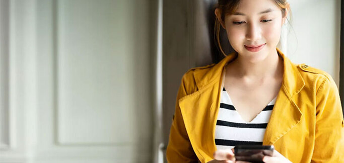 a woman wearing a yellow jacket standing next to the doors and looking at her phone