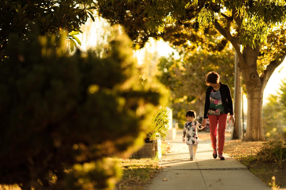 A woman walking hand in hand with a child