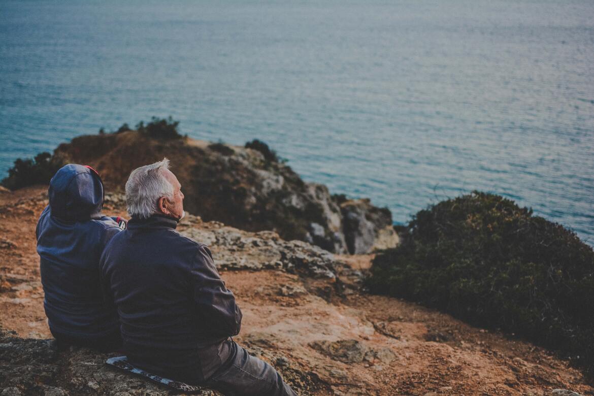 Two older people sat on a hillside